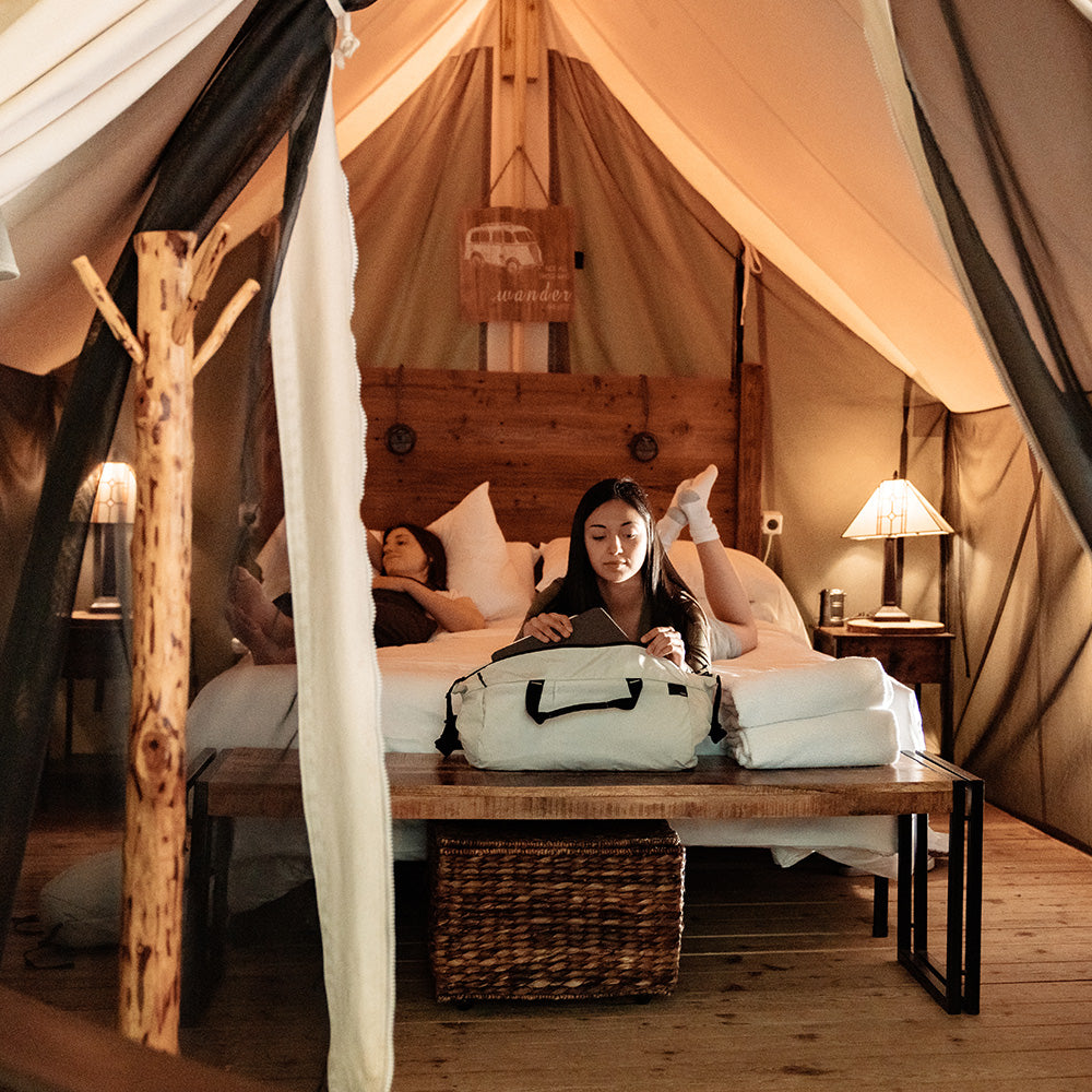 woman laying in glamping tent with white duffle